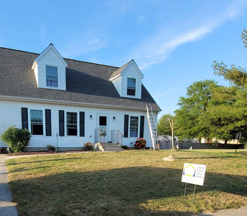 White house with renovators setting up roofing remodel